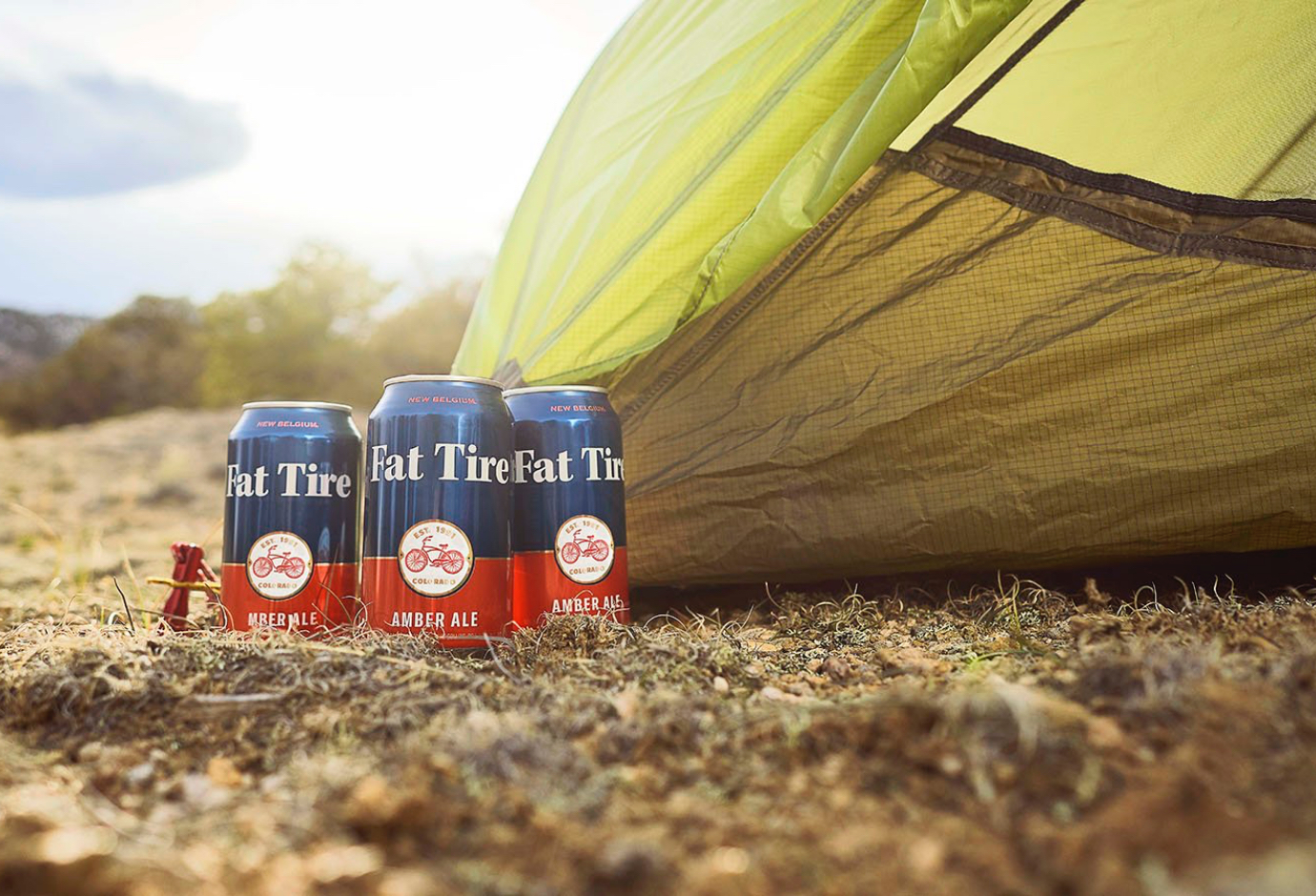 Flat tire amber ale sitting outside a camping tent